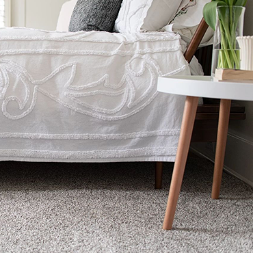 closeup of a bed on carpet with a small side table - Classic Carpets in Midland, TX